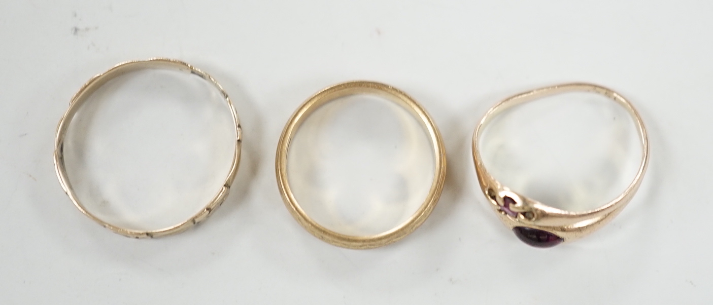 A modern 9ct gold band and two other yellow metal rings including cabochon garnet set